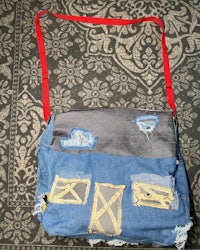 a bag made out of denim with a red strap